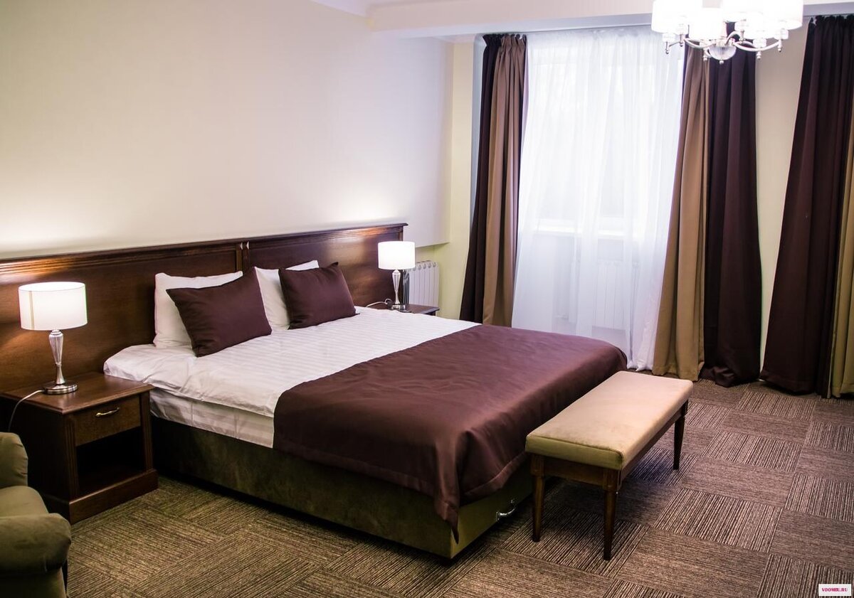 Номер люкс, состоит из двух частей. Зона отдыха с диванчиком и с плоским телевизором расположена справа.