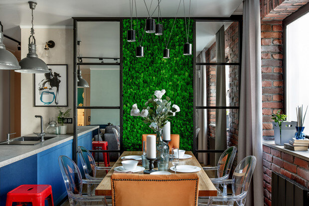 Кухня-столовая. Стулья Gost, Kartell. Гостиная объединена с кухней, и в одном помещении сосредоточено много мебели. Благодаря прозрачным стульям-«невидимкам» обеденная зона выглядит легкой, с акцентом на деревянный стол. Выступ вентиляционной шахты отделан зеркальным стеклом, мхом и черным металлом. ФОТО РОМАН СПИРИДОНОВ