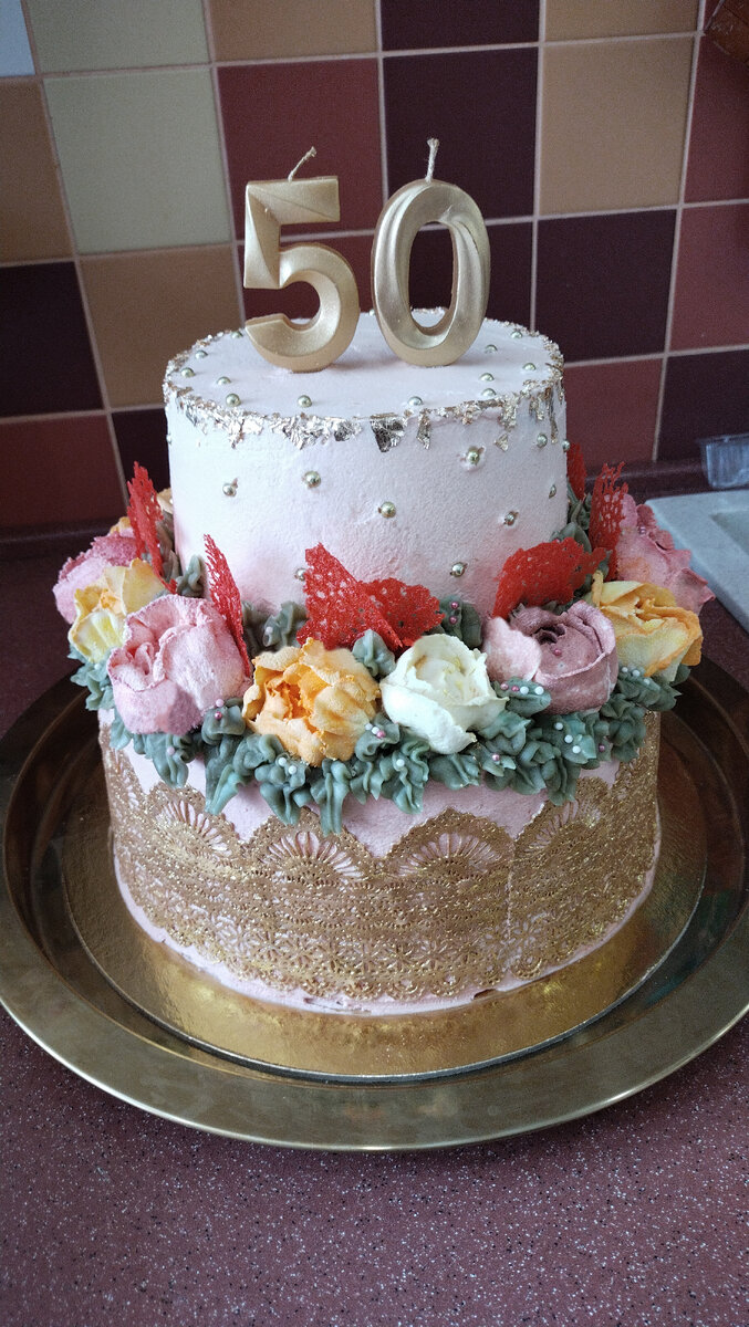 Сам торт получился килограмм на 5. И это одни коржи. С цветами не взвешивала. Торт стоит на крепкой золотистой подложке. Верхний ярус тоже стоит на подложке поменьше размером. И её не видно. Весь торт скреплен шпажками по всей высоте. 3 бамбуковых тонких шпажки. Иначе сполз бы. Нижний ярус украсила кружевом из айсинга. Кружево покрыла золотым кондурином. На стыке двух ярусов расположила цветы из заварного крема, украсила зелеными листьями и красными декоративными сеточками. Они очень вкусные оказались! На верхнем ярусе нанесла бусинки и разложила хаотично золотую поталь. Цифры 50 пришлось везти отдельно в сумке, так как торт никуда не входил. Он получился достаточно высоким. Торт состоит из бисквитных коржей и слоёв с орехами на заварном креме 