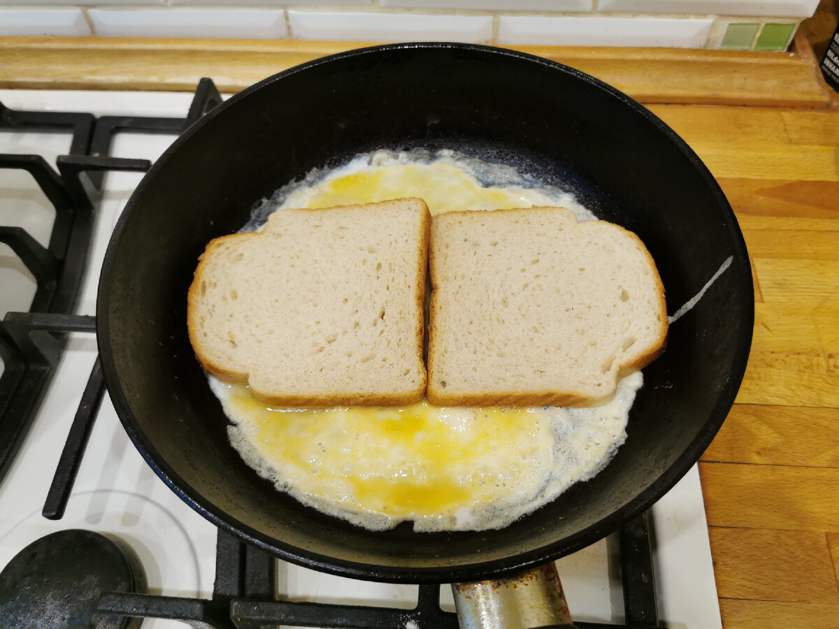Разбиваем в чашку 1 крупное или 2 мелких яйца и немного взбалтываем вилкой. Выливаем яичную смесь на разогретую сковороду с растительным маслом . Сверху кладём тестовый хлеб