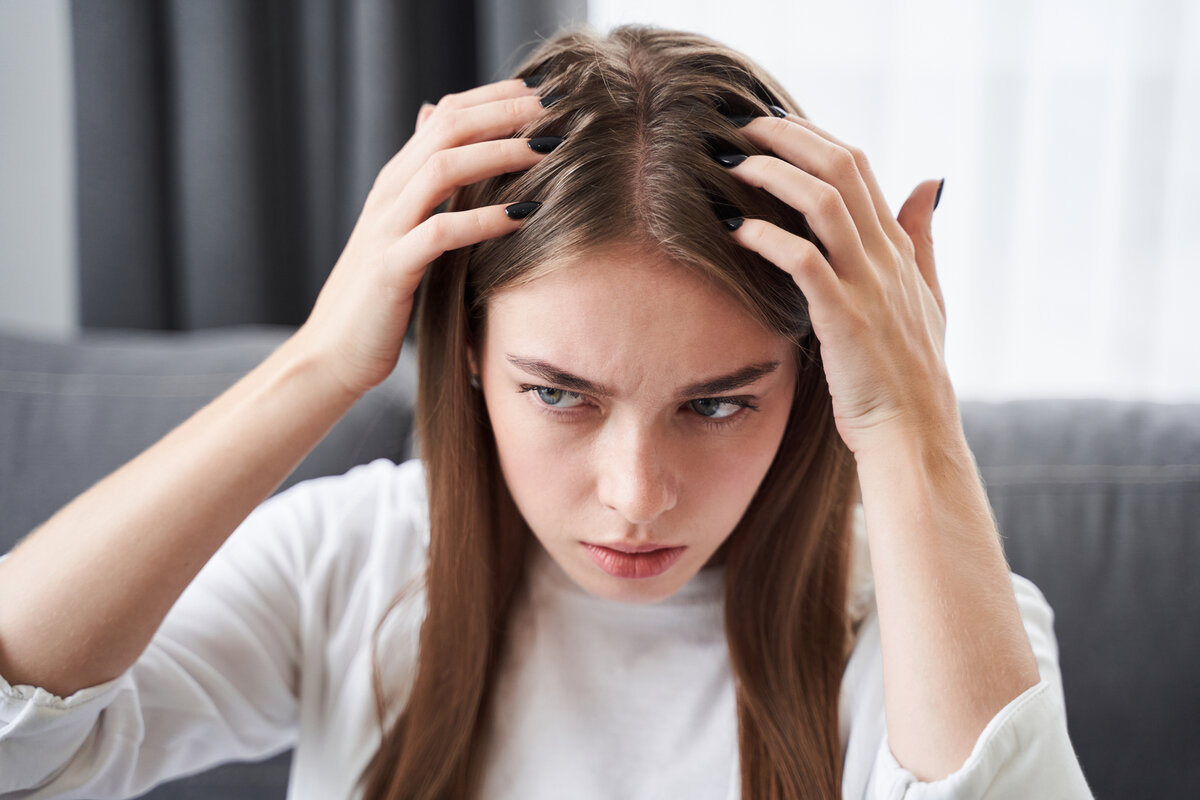 Женщина расстроена из за перхоти. The girl Ran her fingers through her hair.