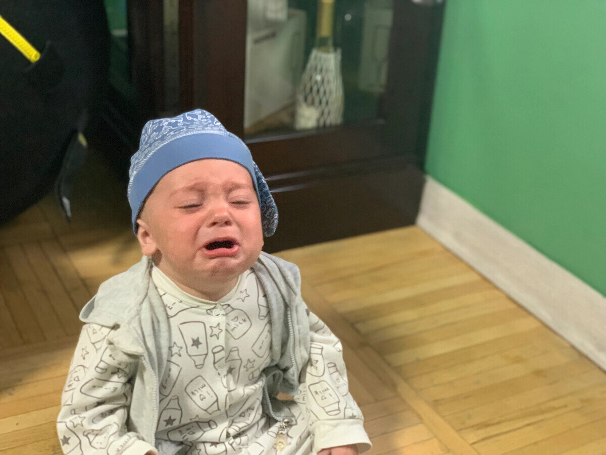 Только посмотрите, как ребенок недоволен, что на него натянули дурацкую шапку