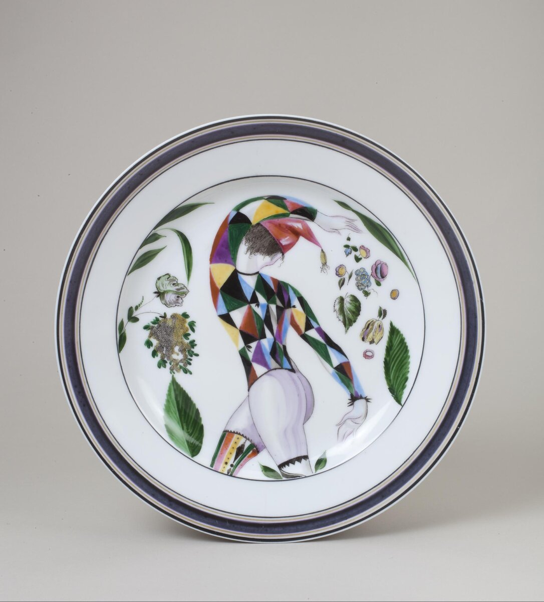 Тарелка "Арлекин". 1922. Фигура явно женская... Роспись надглазурная полихромная. Размеры: 3,8*25,0 см. Собрание Эрмитажа. Предмет поступил в 2002-м году. Передан в составе коллекции Музея Фарфорового завода. Инв. номер Мз-С-3166. Изображение взято из каталога Эрмитажа.