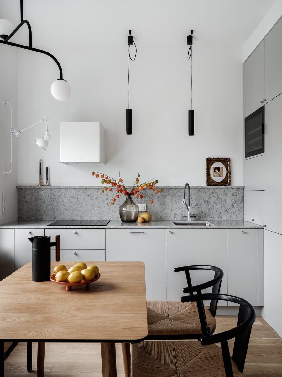 Фото: Дина АлександроваКухня. Гарнитур “Стильные кухни”, кварцевая столешница Technistone, стол Inch, стулья La Redoute, подвесы Maytoni, люстра Pholc, бра Odeon, вытяжка Faber, поднос и картина Carre D'artistes, краска Benjamin Moore.
