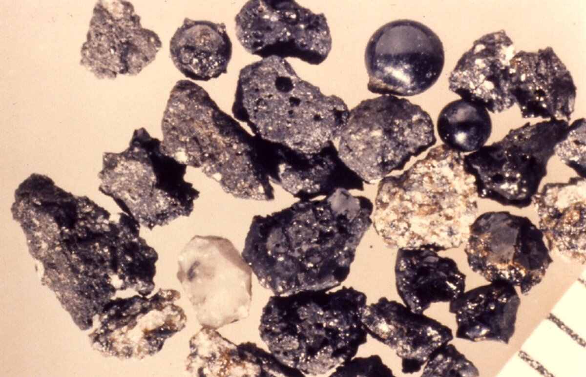 Реголит под увеличением, видно, что отдельные частицы разного цвета, то есть представляют из себя разные минералы.  