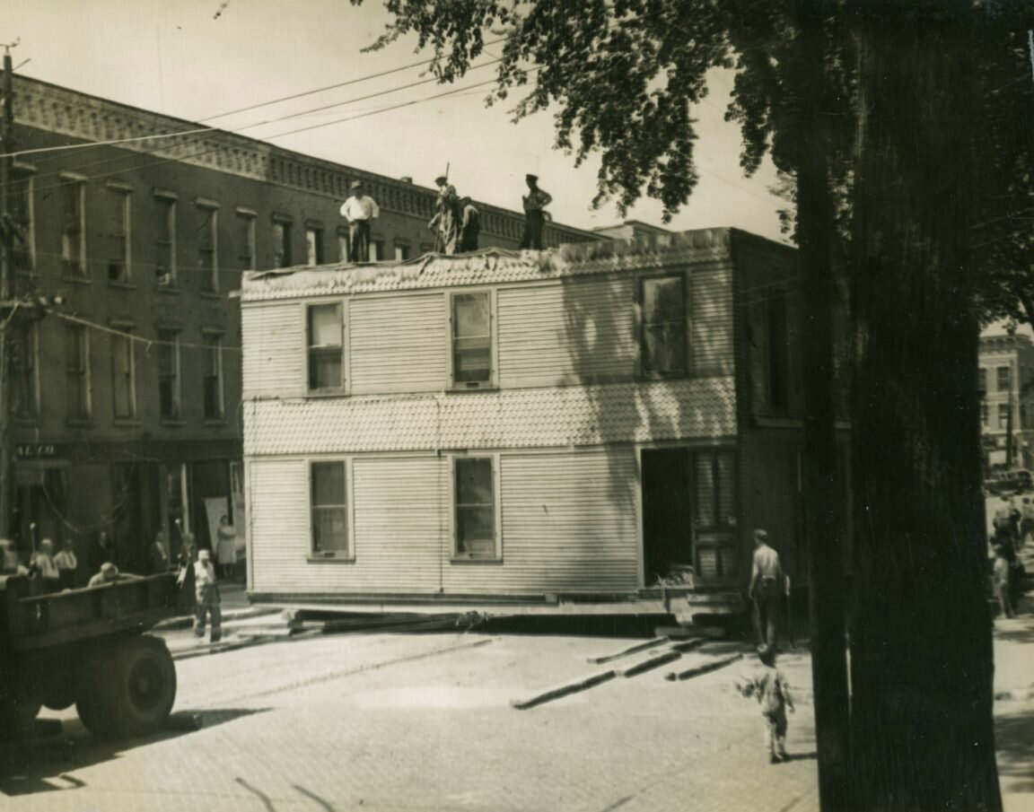 Переезд дома в центре Огденсбурга. Четырехквартирный дом, первоначально разположенный на улице Стейт, 332, был перемещён этой рабочей бригадой на улицу 700 Стейт. Ранее это был дом и офис доктора Дейли. Огденсбург, штат Нью-Йорк. Около 1940 г.