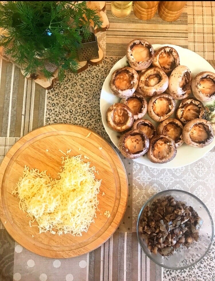 Способ приготовления: 
Отделяем шляпки грибов от ножек.
Ножки нарезаем мелко.
Сыр натираем в крупную тёрку.
Ножки, сыр, майонез или сметану смешиваем и добавляем специи по вкусу.

Начиняем шляпки грибов начинкой.
Немного сыра оставляем для сырной шапочки, покрываем им все грибы.
Выкладываем грибы в форму и запекаем в разогретой до 180 градусов духовке 20 - 30 минут.