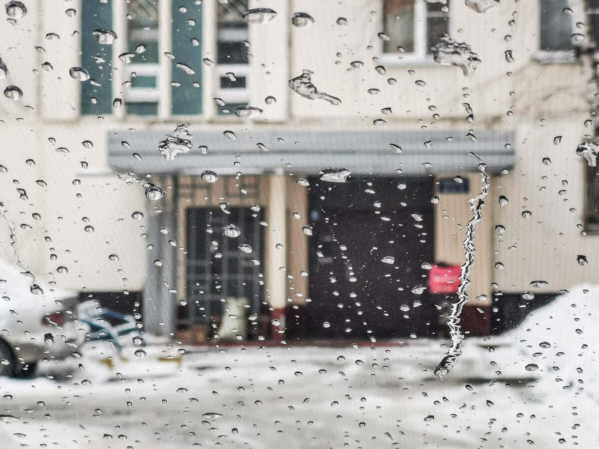 Подъезд дома 42 на Алтуфьевском шоссе сквозь капли на ветровом стекле автомобиля.
