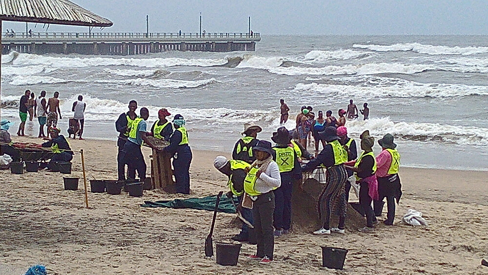 Рабочие чистят пляж в Дурбане после шторма. Фото автора