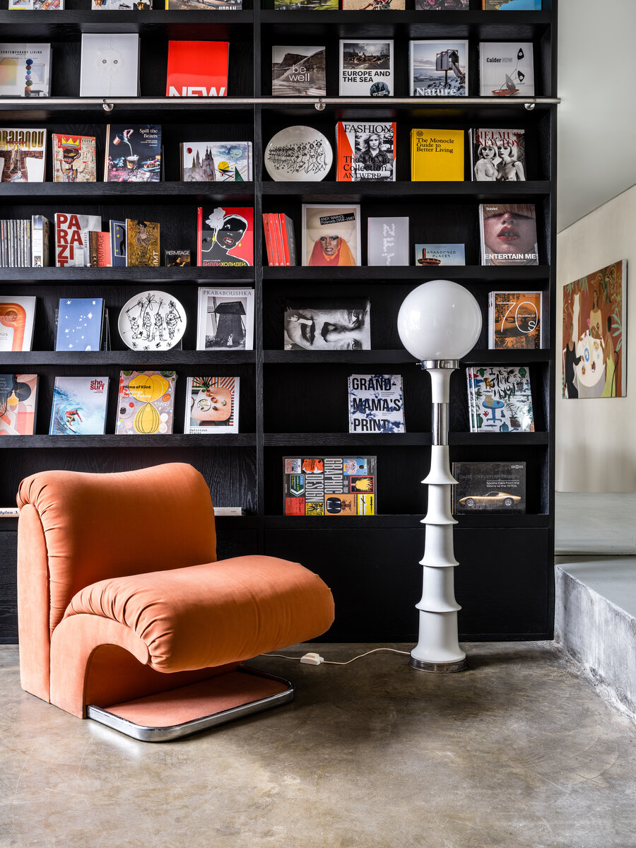 Винтажные кресло в виде книги и торшер на фоне книжных стеллажей.