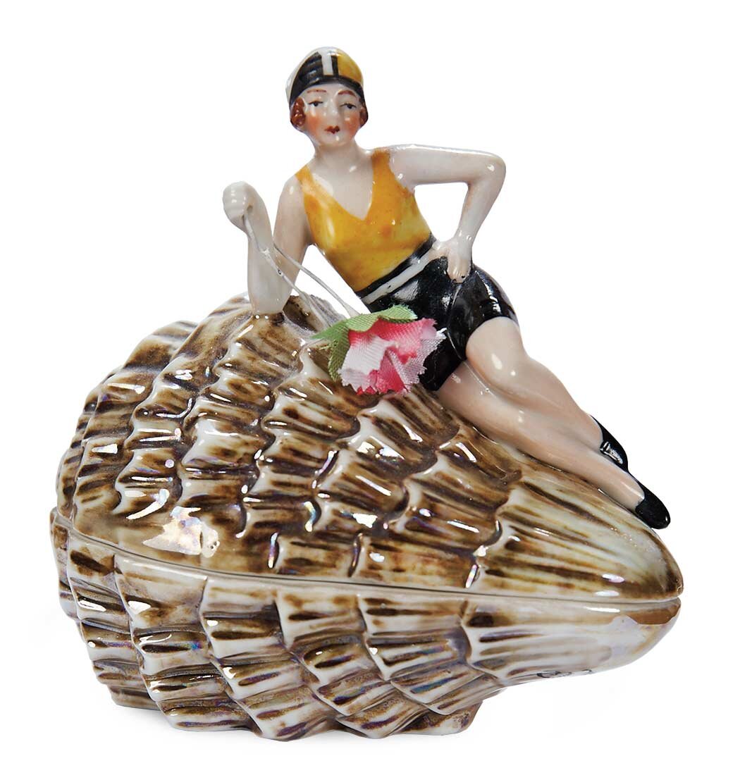 Пудреница с пуховкой в виде девушки, сидящей на морской раковине. Высота 11 см, фарфор, надглазурная роспись. 1920-е, Германия.  Strong National Museum of Play, Нью-Йорк, официальный сайт -  www.museumofplay.org