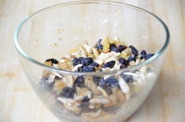 Как испечь рождественский штоллен? Для начала заранее (лучше с вечера) замочите изюм, очищенные орехи и цедру в коньяке и ванильной настойке. Если вы будете использовать ванильный сахар, то добавляйте его прямо в тесто). Миндаль в кожуре лучше очистить, иначе оболочка орехов даст горечь. Для этого залейте орехи горячей кипячёной водой и оставьте на 10-15 минут. Оболочка орехов набухнет и легко снимется руками.