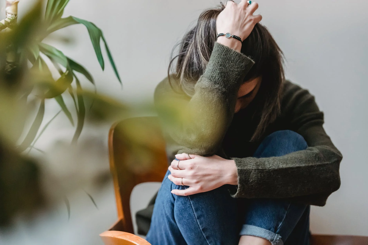 https://www.pexels.com/photo/unrecognizable-upset-lady-embracing-knees-sitting-on-chair-6382642/
