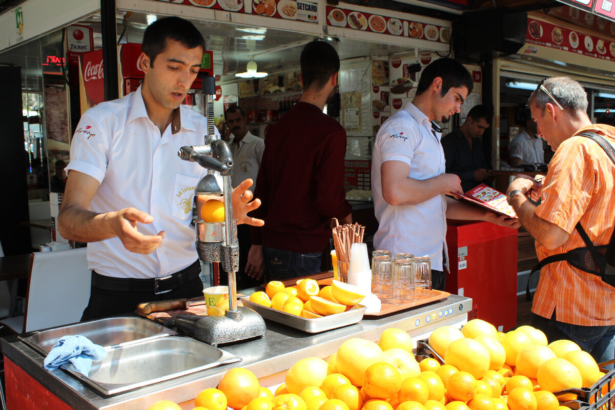 Мы стоим у лотка, где нам приготовят два стакана апельсинового сока. А можно еще было заказать из грейпфрута.