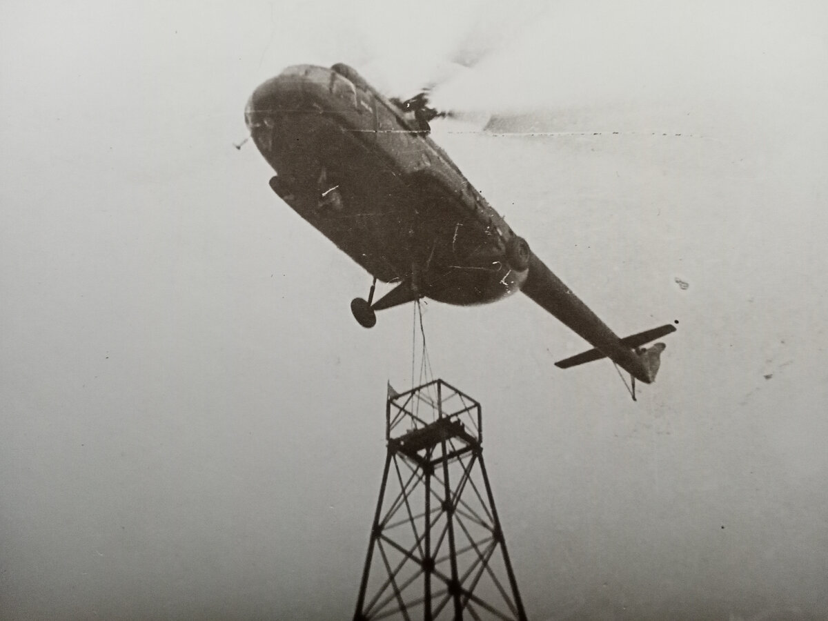 Вертолёт ставит каркас  вышки  на буровую.