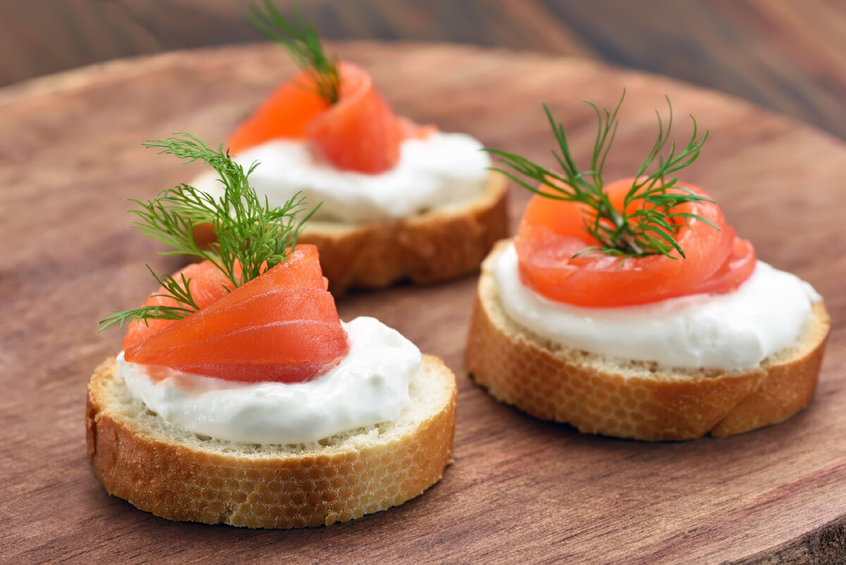 Закуска с лососем и творожным сыром считается классикой практически любого праздничного стола. Готовится она быстро, а получается вкусной и питательной.