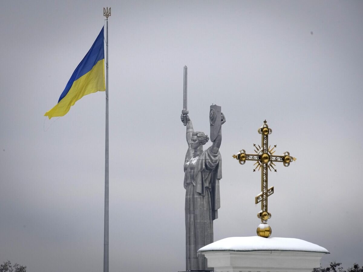 Крест монастырского комплекса Печерской Лавры на фоне украинского государственного флага и монумента Родина-мать в Киеве© AP Photo / Efrem Lukatsky