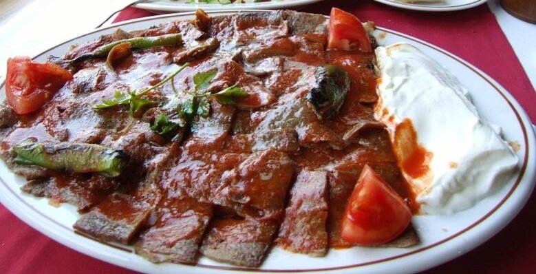 Искандер Кебаб - тонкая нарезка чего-то отдалённо напоминающего мясо, много томатного соуса и толстая лепешка внизу.  