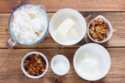 ШАГ 1:
Подготовить указанные ингредиенты. Особое внимание следует уделить творогу: он должен быть свежий, предпочтительней домашний. Жирность лучше брать 9%, но творог не должен быть влажным, выбирайте жирный сухой творог. Также и со сливочным маслом и сметаной - они должны быть свежими. Грецкие орехи и изюм можно заменять и менять количество по своему вкусу. Сахар также можно варьировать в зависимости от предпочтений, можно использовать сразу ванильный сахар.