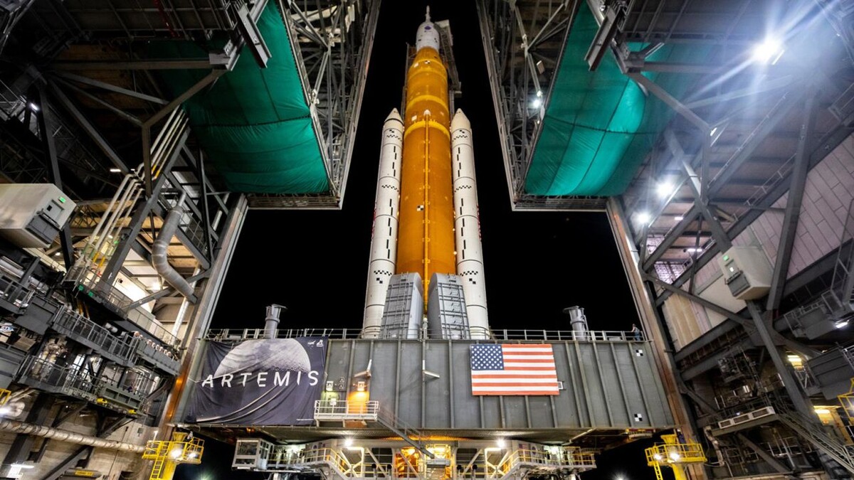 Мобильная пусковая установка с ракетой NASA SLS и космическим кораблем Orion выезжает из High Bay 3 здания сборки транспортных средств на стартовый комплекс 39B во вторник, 16 августа 2022 года, в Космическом центре Кеннеди НАСА во Флориде. 