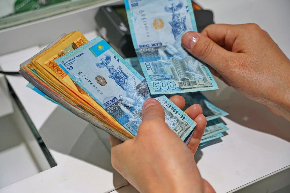    Банковский клиент считает деньги на кассе:NUR.KZ/Владимир Третьяков