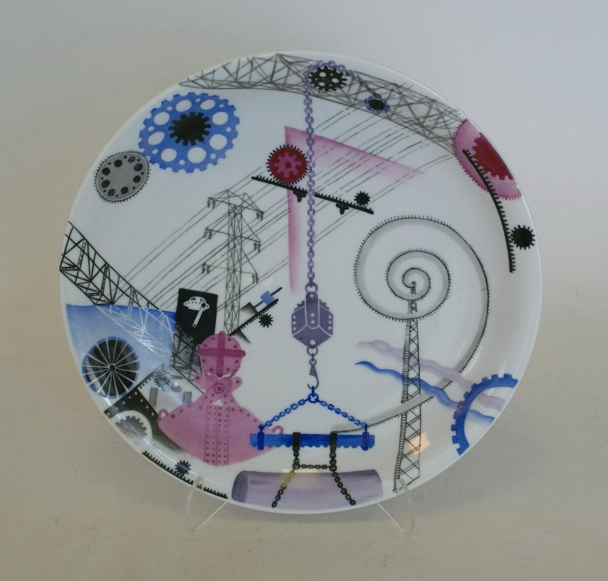 Сухарница из комплекта "Сервиза №5" ("Индустриальный"), 1931. Автор рисунка и исполнитель росписи - Протопопова Л.В. Роспись надглазурная полихромная. Размеры:  4,5*27,2 см. (блюдце). Предмет поступил в Эрмитаж в 2002. Передан в составе Музея Фарфорового завода. Инв. номер Мз-С-2458. Изображение взято из каталога Эрмитажа.