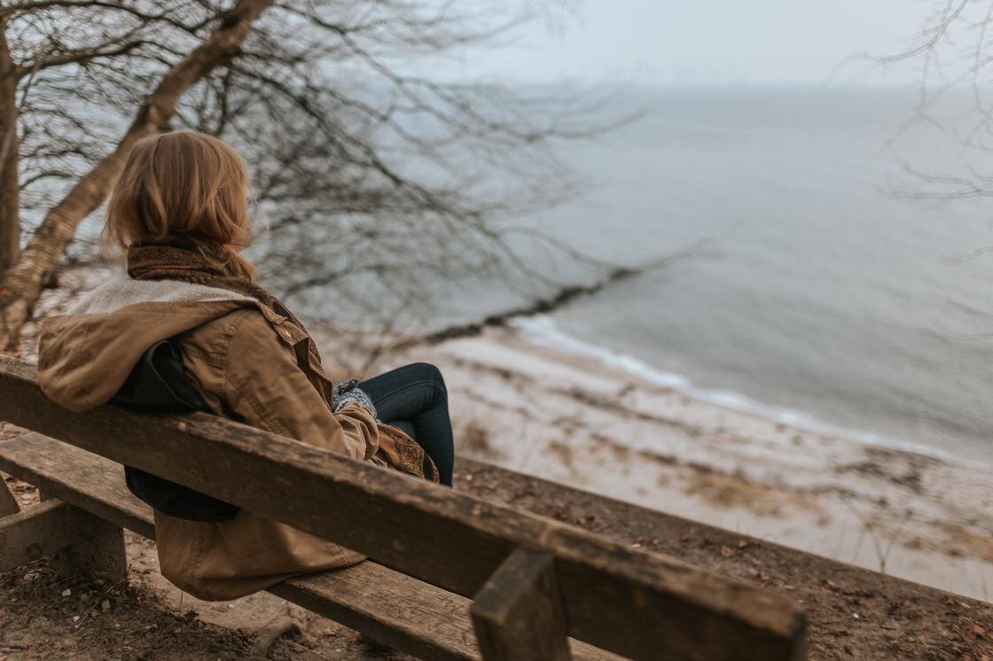   Женщина сидит на берегу моря:Unsplash/Krists Luhaers