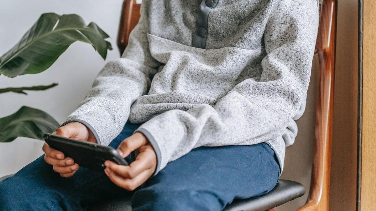    Подросток сидит на стуле и играет в телефоне:pexels.com