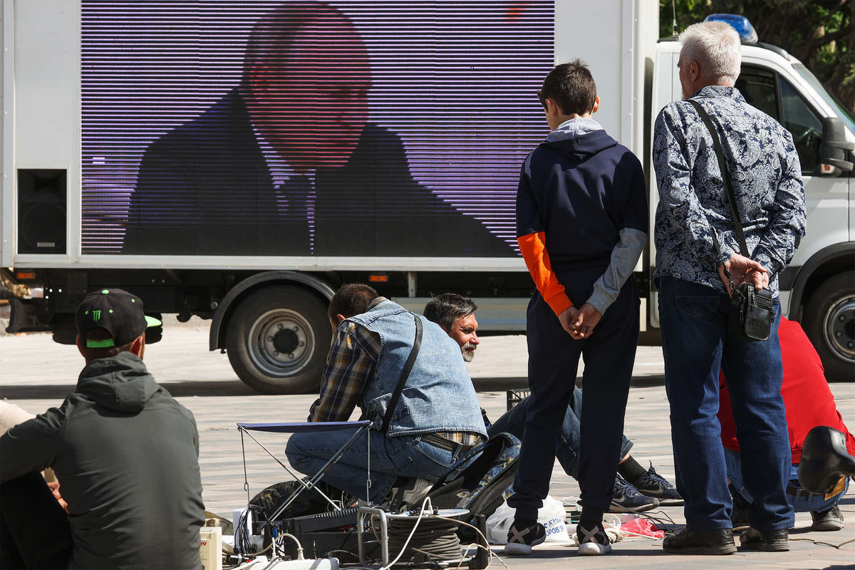 Трансляция видео с президентом РФ Владимиром Путиным на площади у Донецкого академического областного драматического театра в Мариуполе, 25 мая 2022 года / Фото: Владимир Гердо/ТАСС