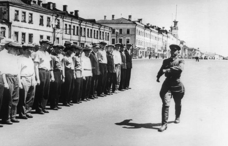 1941 год. Лейтенант И. Ф. Третьяк показывает народным ополченцам Дзержинского района строевой шаг. Тренировка проходит на Садовом кольце, неподалеку от Сухаревской площади.