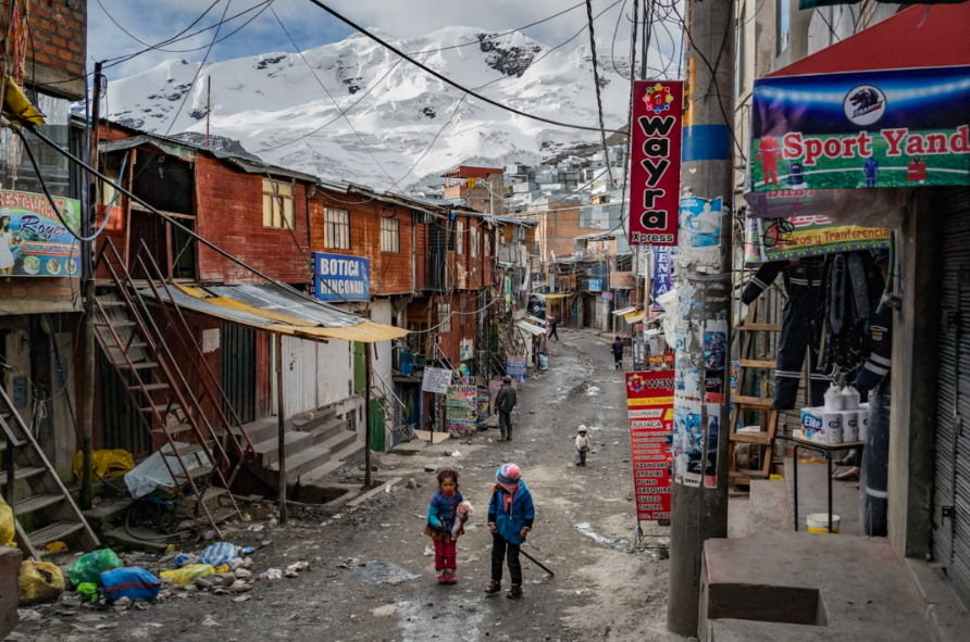 Две девушки идут по главной улице Ла-Ринконада в тени горы Ананея, изрытой шахтными шахтами. В городе нет больницы, мусоропровода или канализационной системы. Фото: Седрик Гербехай