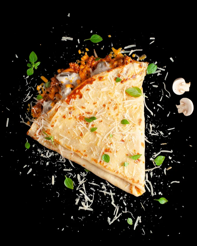 Блин мясная лазанья с грибами: Авторский блин, фирменный мясной соус с томатами, сливочный соус жульен с грибами, сыр чеддер, сыр пармезан, душистый зелёный базилик 