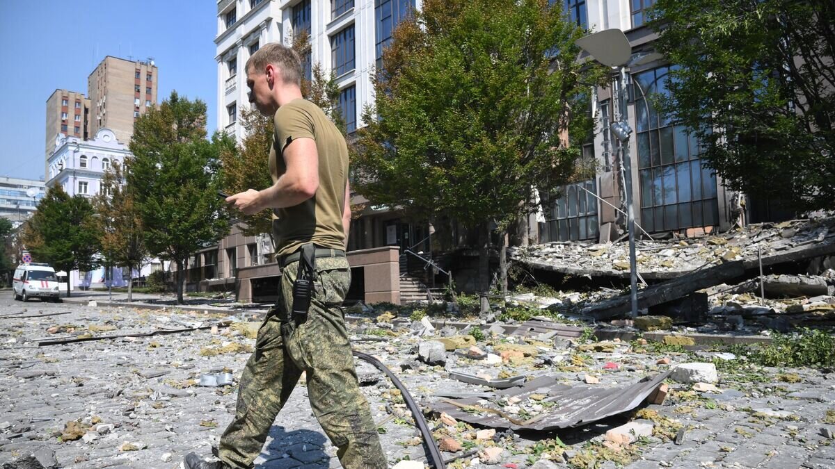    Военнослужащий около здания администрации главы Донецкой народной республики, поврежденного в результате обстрела ВСУ в Донецке© РИА Новости / Илья Питалев