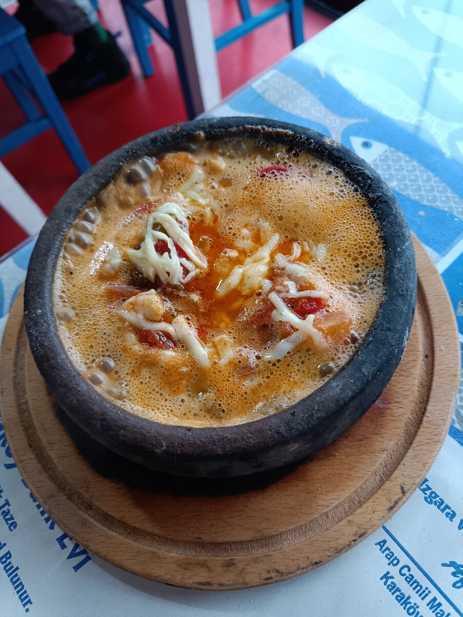 Креветки с овощами под сыром кипят, уже поданными на стол. 