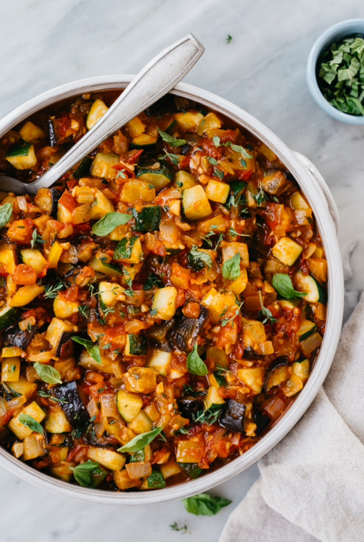 Рататуй — французское блюдо, принадлежащее к прованской кухне, в классическом варианте готовится из свежего перца, сладких томатов, лука, чеснока и, конечно, кабачков. Первые упоминания о нем датируются 18 веком, когда блюдо было популярно среди бедных крестьян. Сегодня в рататуй добавляют баклажаны, которые ощутимо добавляют ему сытости. Важный элемент блюда — травы. В прованской кухне вкус привычных продуктов всегда раскрывается с новой стороны с помощью специй и трав. В рататуй можно добавить мускусную ноту трюфеля — любимого кулинарного парфюма всех поваров; розмарин с его глубоким, насыщенным ароматом; свежесть мяты и базилика. Похожие блюда существуют и в других кухнях мира: в Италии разновидность овощного рататуя называется капоната, в Испании — писто, а в Каталонии — самфайна. Рататуй по этому видеорецепту получается ароматным, сытным и красивым. Его можно есть горячим и холодным, он идеален для баранины с козьим сыром, рисом и яйцом и так же хорош в качестве самостоятельного блюда.