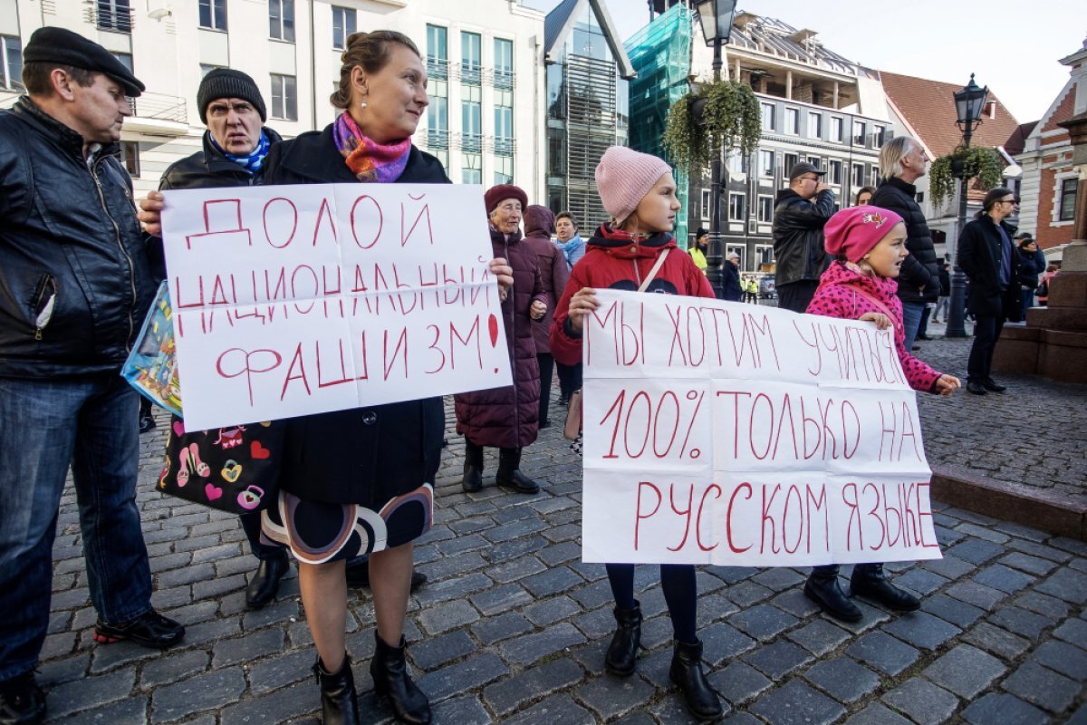    Участники марша в защиту русских школ держат плакаты с надписями.