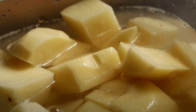 В процессе приготовления ингредиентов доведите до кипения кастрюлю с водой. Очистите от кожуры и нарежьте небольшими кубиками картофель. Затем помойте проточной водой и на разделочной доске нашинкуйте тонкой полоской белокочанную капусту.