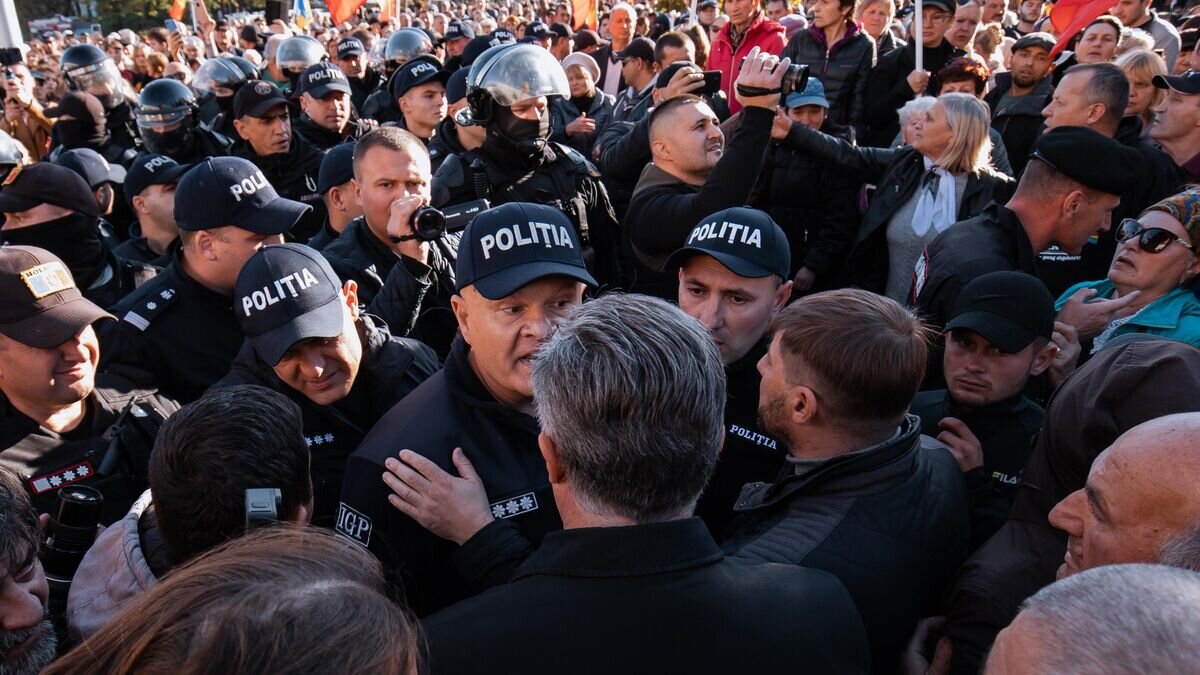    Полицейский общается с одним из участников антиправительственной акции протеста, организованной оппозиционной партией "Шор", неподалеку от парламента Молдовы в Кишиневе© Sputnik / Дмитрий Осматеско