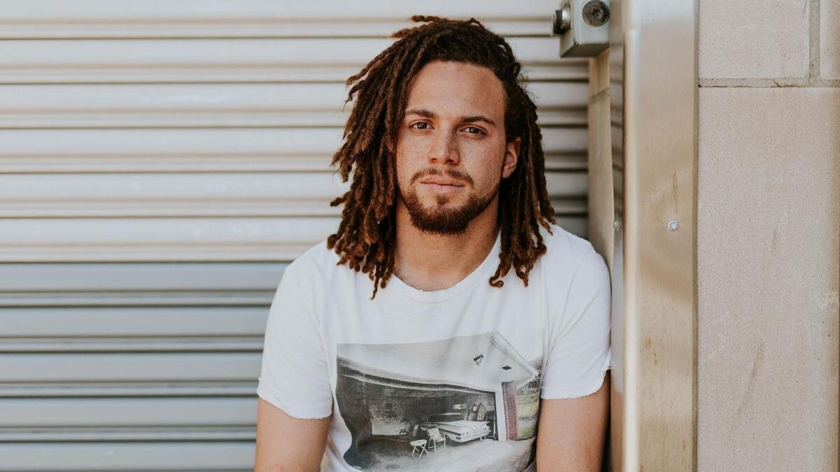    Парень в белой футболке с дредами:Unsplash/Brooke Cagle