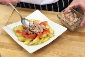 Шаг 2 Картофель нарезать полукругом. Разложите их на блюде. Помидор нарежьте на четвертинки и положите его на картофеле. В центре поместите измельченного тунца.