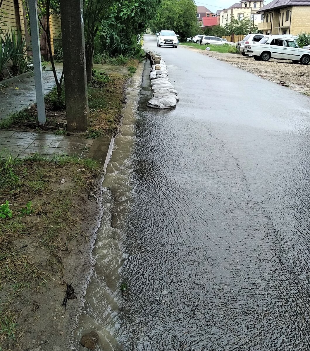 Наша улица, и вот такая вручную сооруженная плотина, не пускающая воду во дворы.