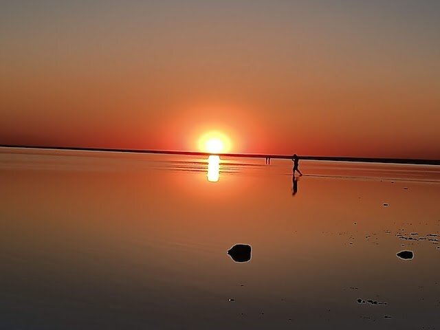  Сегодня  12 июня 2022 года, закат солнца в 19:58. Шагая босыми ногами по белому соляному полю, прикрытому небольшим слоем воды, я отдалилась от берега.  Куда не взгляну - непрерывная линия горизонта.