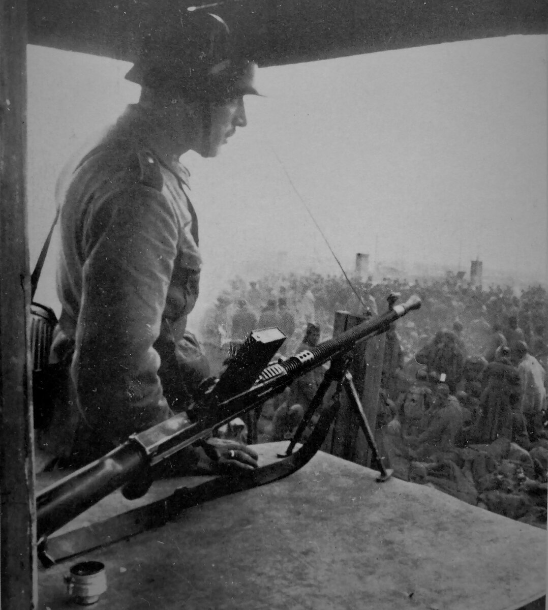 Немецкий солдат охраняет советских военнопленных в транзитном лагере в Порхове, 1941 год