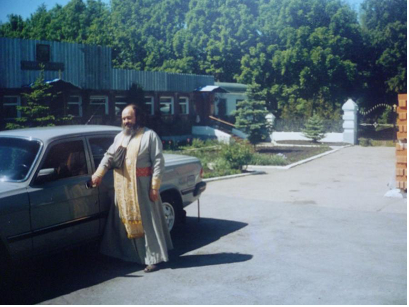 Иерей Василий (Новиков) возле своего автомобиля на фоне здания трапезной