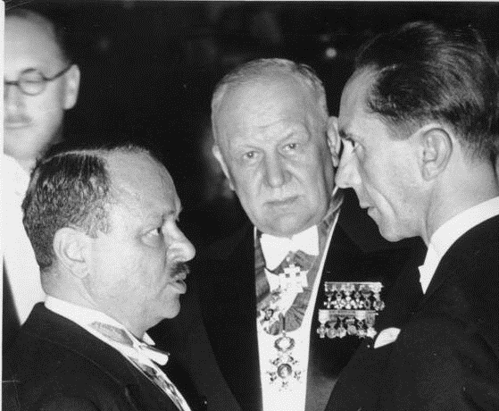 Геббельсу (справа) повезло: ему выпало давать указания композитору Легару (в центре) и музыкальному издателю Бернгарду Герцмански (слева). Последний два года спустя попадёт в концлагерь Дахау. А вид у самого Геббельса явно растерянный. 
С выражением благодарности сайту https://www.shamardanov.ru 