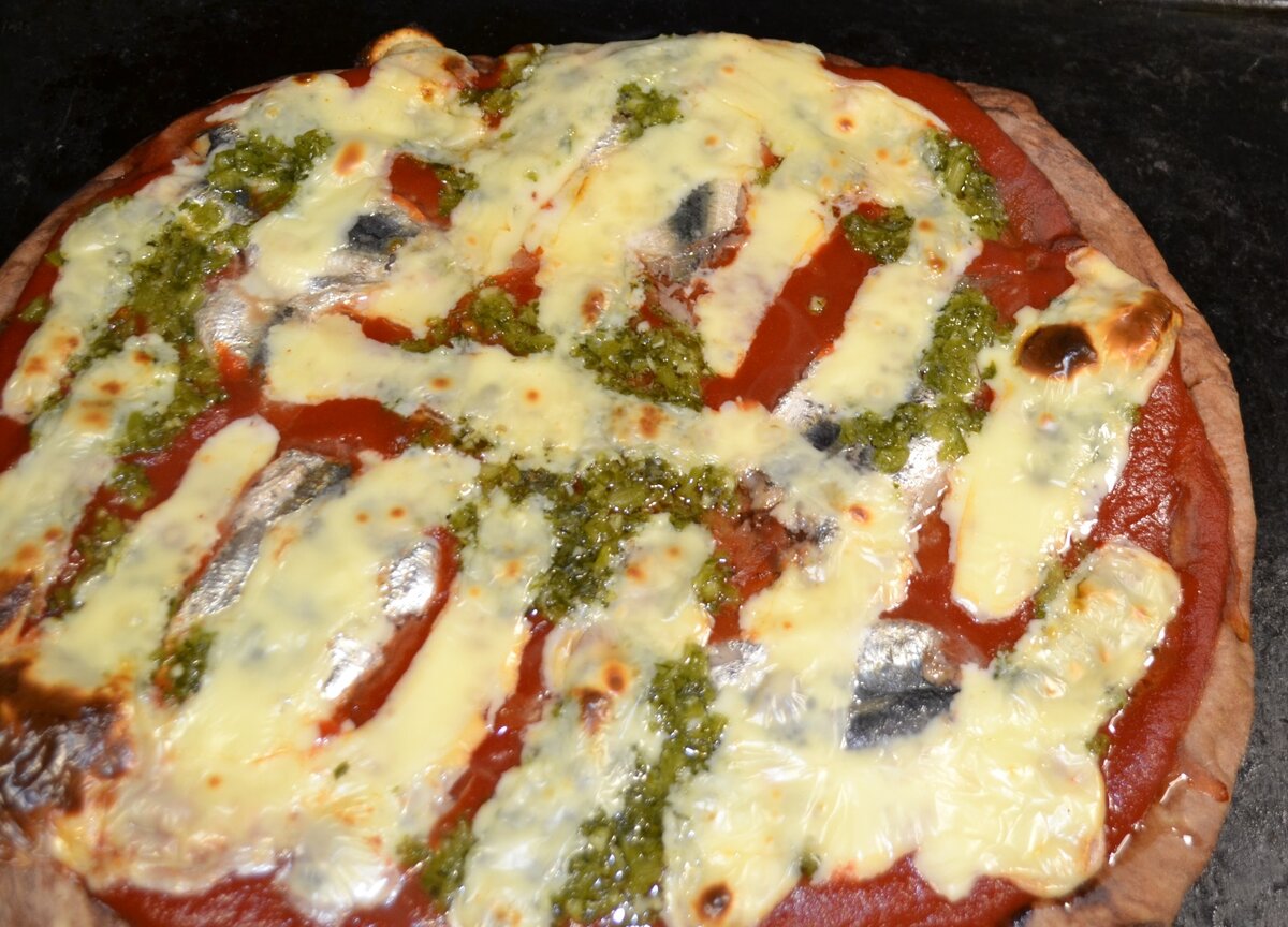 Готовая пицца с шоколадной лепешкой, маринованной рыбой, петрушкой и моцареллой.