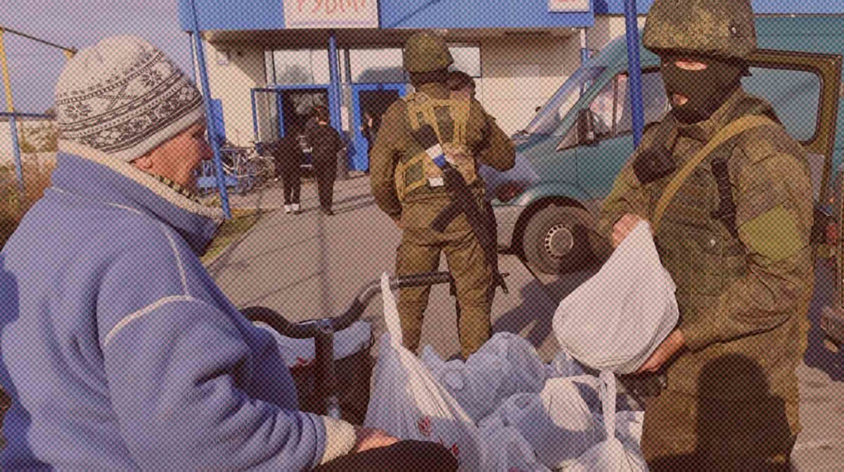    Мобилизованный военнослужащий РФ передает гуманитарную помощь местной жительнице в городе Каменке-Днепровской Запорожской области