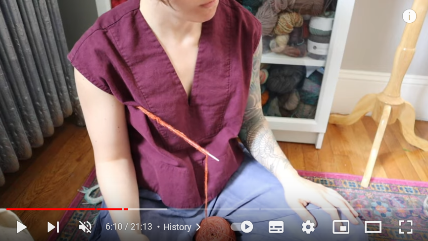 Это если вязание конкретно с длинной спицей с ограничителем, ее ставят в подмышку, на бок, бедро и т.д. Листайте. Скриншот с этого видео, там типа ирландский способ https://www.youtube.com/watch?v=ZcIkhy31ns0