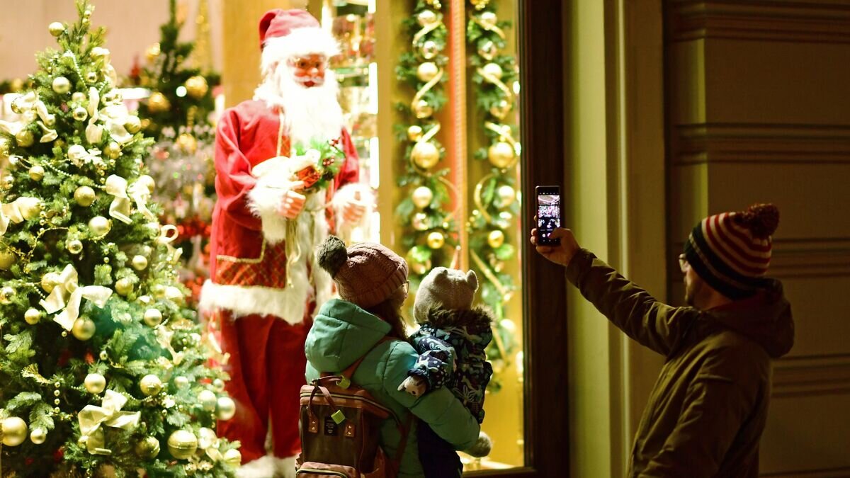    Прохожие фотографируют Санта Клауса в витрине на Никольской улице в Москве© РИА Новости / Алексей Майшев