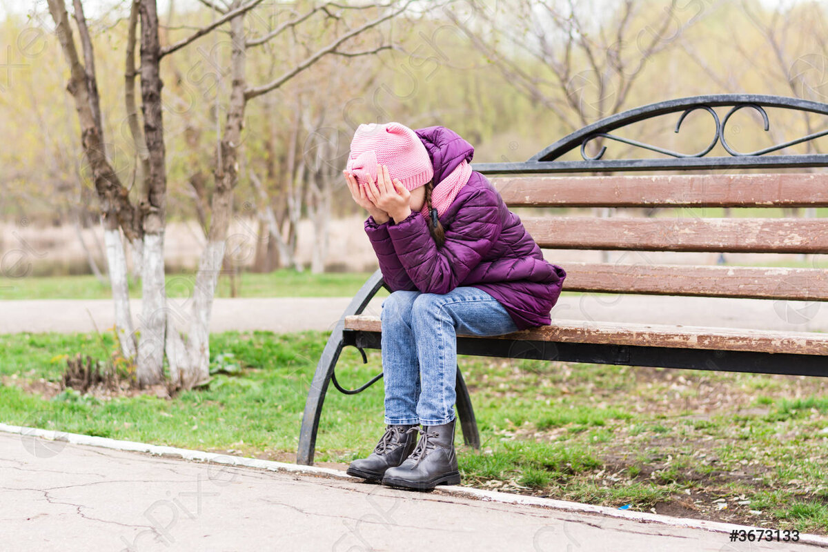 Девушка плачет закрыв лицо руками на скамейке